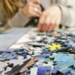Hands working on a colorful jigsaw puzzle, showcasing leisure and concentration.