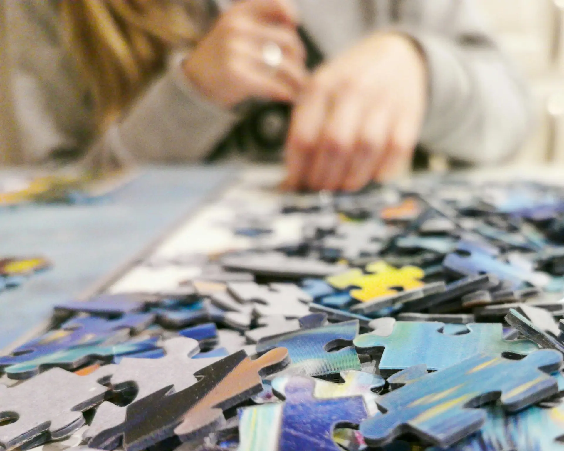 Hands working on a colorful jigsaw puzzle, showcasing leisure and concentration.
