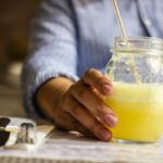 Person holding a refreshing glass jar of lemonade with a straw in an indoor setting.